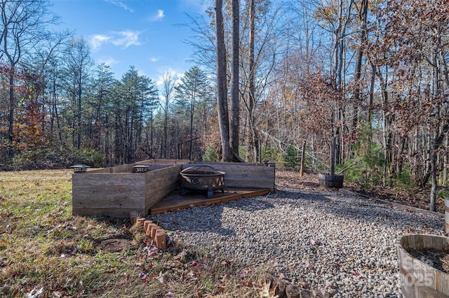 view of yard featuring a fire pit and a wooded view