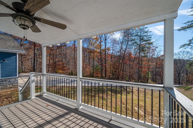 deck featuring a ceiling fan and a view of trees