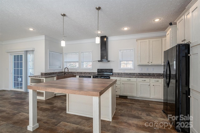 kitchen with butcher block counters, dark wood-style flooring, wall chimney range hood, crown molding, and black appliances