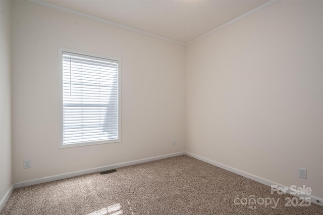 carpeted spare room featuring baseboards, visible vents, and crown molding