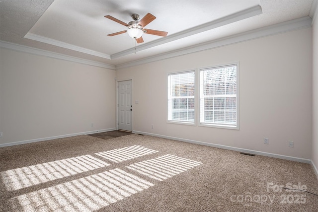 carpeted spare room featuring baseboards, a raised ceiling, and crown molding