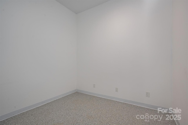 spare room featuring light speckled floor and baseboards