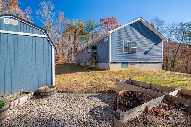 view of property exterior with entry steps, crawl space, and a yard