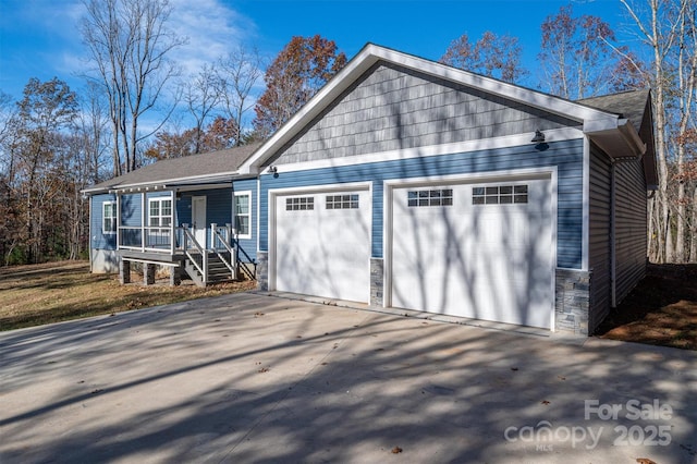 view of front facade featuring an attached garage, covered porch, driveway, and stone siding