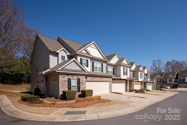 multi unit property featuring board and batten siding, a residential view, driveway, stone siding, and an attached garage