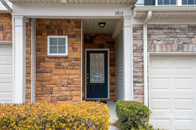 property entrance featuring a garage and stone siding