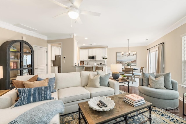 living room with visible vents, crown molding, recessed lighting, ceiling fan with notable chandelier, and wood finished floors