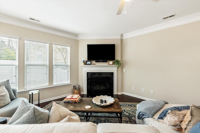 living area with visible vents, wood finished floors, and ornamental molding