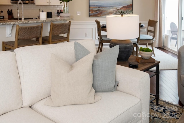 living area featuring a wainscoted wall, wood finished floors, and a decorative wall