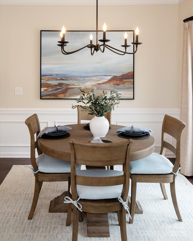 dining room with a notable chandelier, wood finished floors, and wainscoting