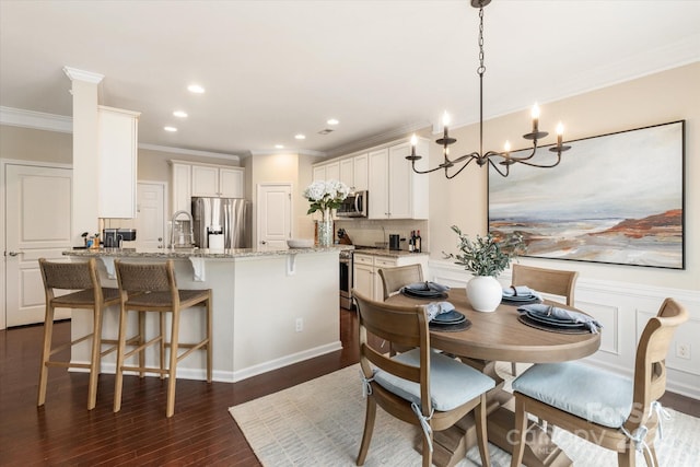 dining area featuring dark wood finished floors, recessed lighting, wainscoting, crown molding, and a notable chandelier