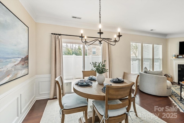 dining space with crown molding, a notable chandelier, dark wood-style floors, and visible vents