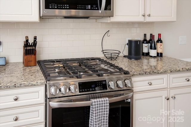 kitchen with decorative backsplash, white cabinetry, and stainless steel appliances