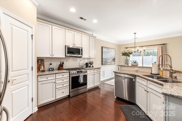 kitchen featuring visible vents, ornamental molding, a sink, stainless steel appliances, and dark wood-style flooring