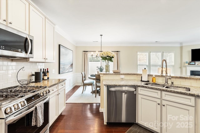 kitchen featuring a sink, dark wood finished floors, stainless steel appliances, an inviting chandelier, and crown molding