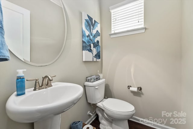 bathroom featuring toilet, baseboards, and a sink