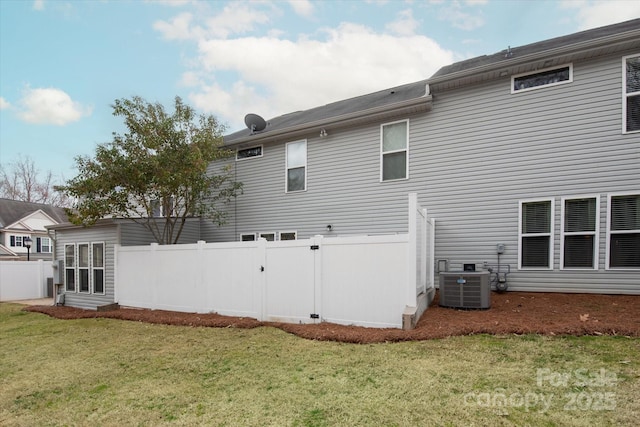 rear view of house with central air condition unit, a yard, and fence