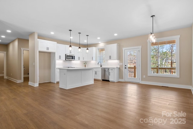 kitchen featuring stainless steel appliances, wood finished floors, light countertops, and white cabinetry