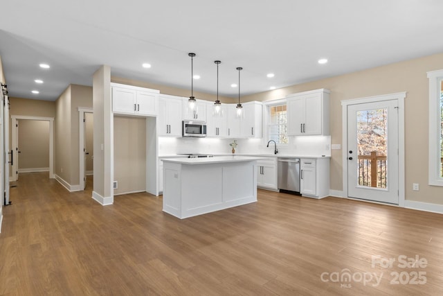 kitchen with recessed lighting, stainless steel appliances, light countertops, white cabinets, and light wood-type flooring