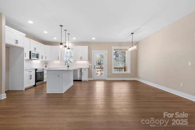 kitchen with dark wood-type flooring, appliances with stainless steel finishes, white cabinets, and light countertops