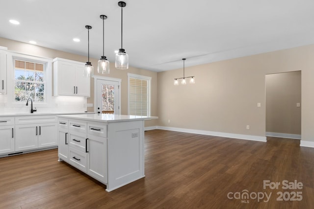 kitchen featuring dark wood finished floors, a kitchen island, white cabinetry, and light countertops