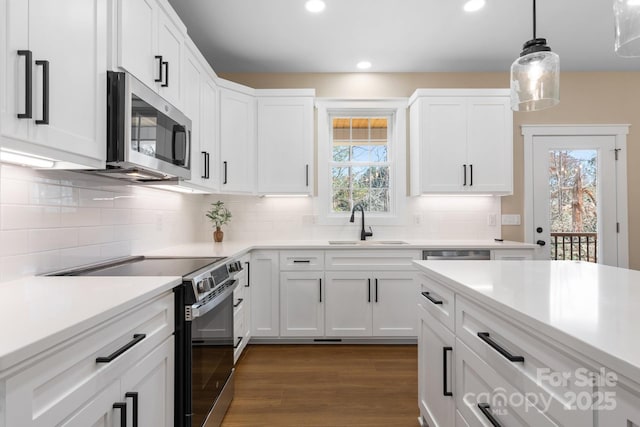 kitchen featuring stainless steel microwave, range with electric cooktop, dark wood finished floors, white cabinetry, and a sink