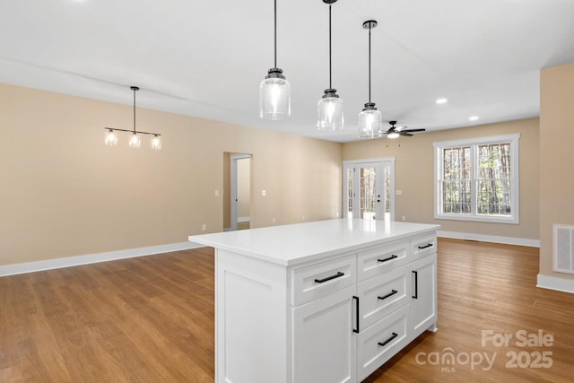 kitchen with open floor plan, pendant lighting, baseboards, and light wood-style floors