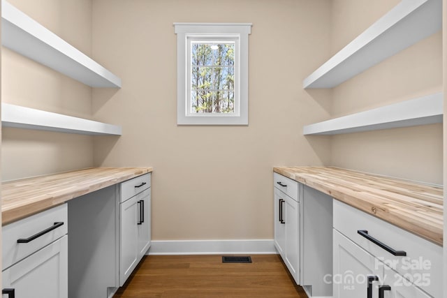 interior space featuring visible vents, baseboards, and dark wood-type flooring