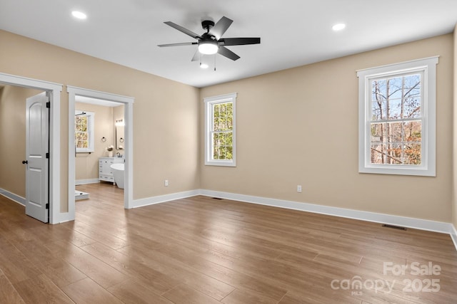 unfurnished bedroom featuring wood finished floors, visible vents, baseboards, ensuite bath, and recessed lighting