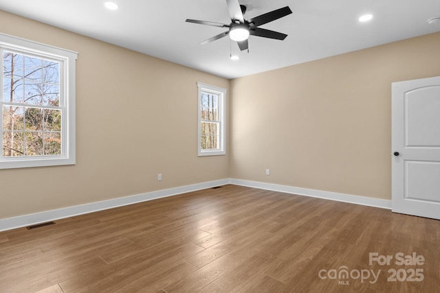 empty room with visible vents, baseboards, and wood finished floors