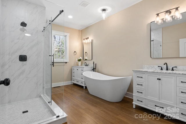 bathroom with a marble finish shower, visible vents, and wood finished floors