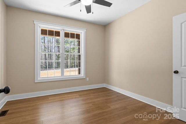 spare room with visible vents, a ceiling fan, baseboards, and dark wood-style flooring