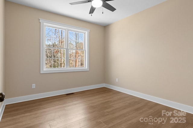 unfurnished room featuring visible vents, a ceiling fan, baseboards, and wood finished floors