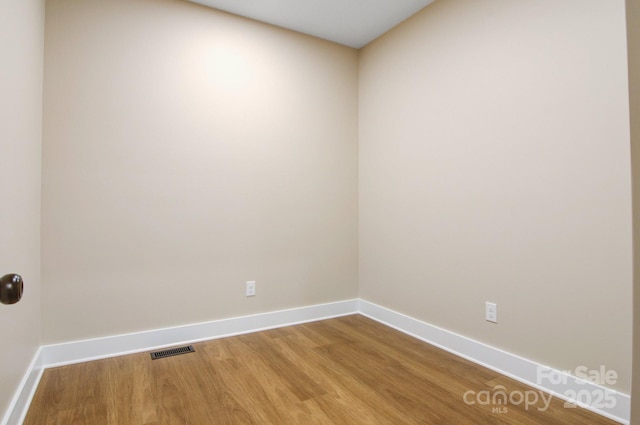 empty room with visible vents, baseboards, and wood finished floors