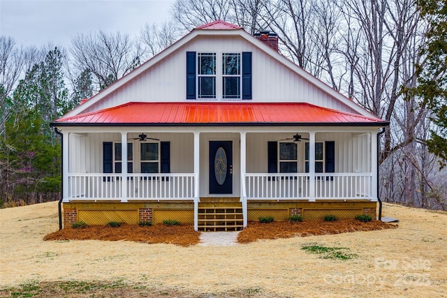 view of front facade featuring covered porch, ceiling fan, a chimney, and metal roof