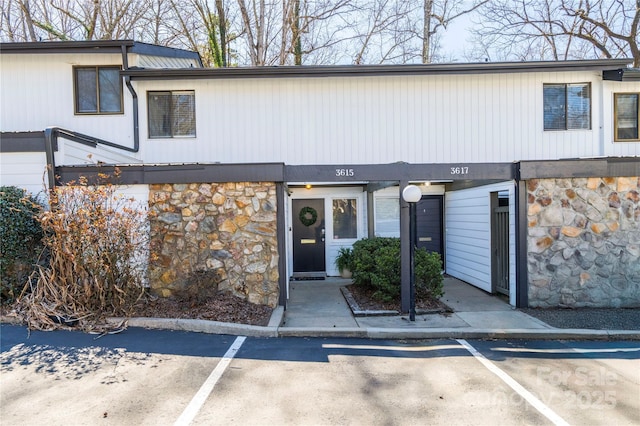 multi unit property with uncovered parking and stone siding