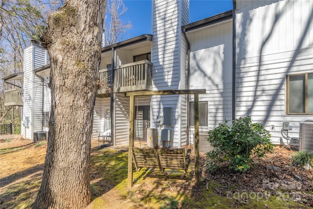 entrance to property featuring central AC, a chimney, and a balcony