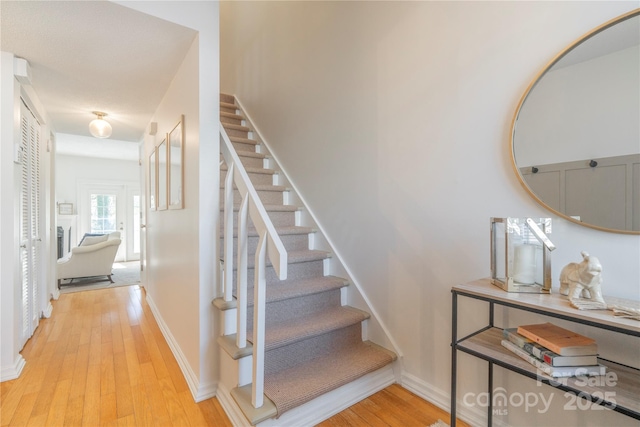 stairs featuring wood-type flooring, a fireplace, and baseboards