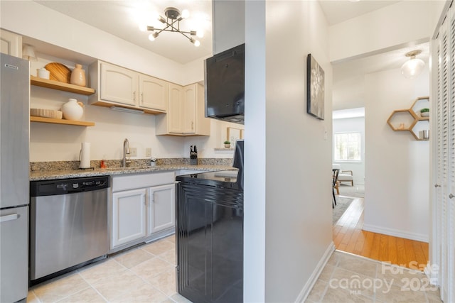 kitchen featuring light tile patterned floors, stainless steel appliances, a sink, light stone countertops, and a chandelier