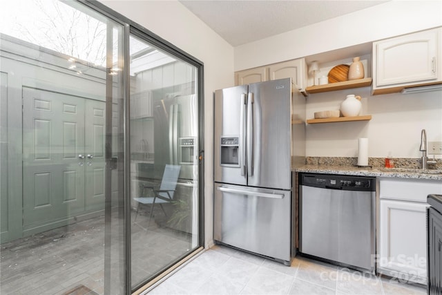 kitchen with light stone counters, open shelves, stainless steel appliances, light tile patterned flooring, and a sink