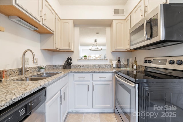 kitchen featuring light stone counters, visible vents, appliances with stainless steel finishes, white cabinets, and a sink