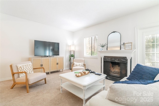 living area featuring baseboards, a high end fireplace, a wealth of natural light, and light colored carpet