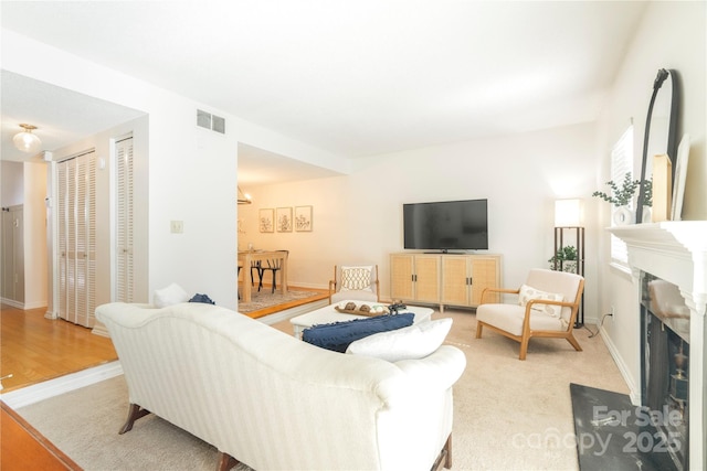 carpeted living room with visible vents, a fireplace, and baseboards