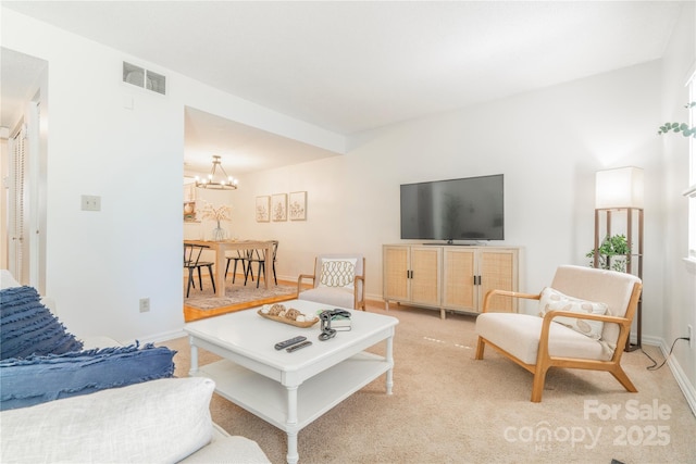 living area featuring visible vents, a notable chandelier, light carpet, and baseboards