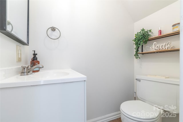 bathroom with toilet, vanity, and baseboards