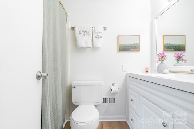 bathroom with toilet, wood finished floors, vanity, visible vents, and baseboards