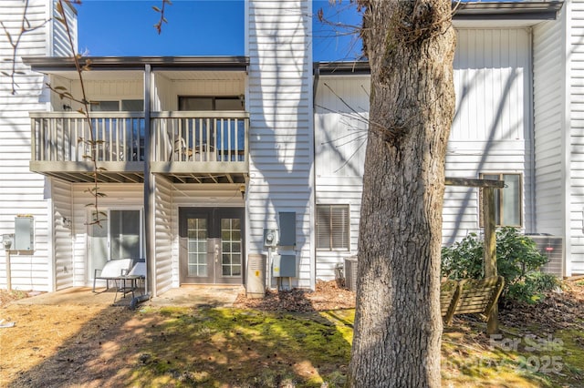 back of property featuring french doors, a chimney, central AC unit, and a balcony