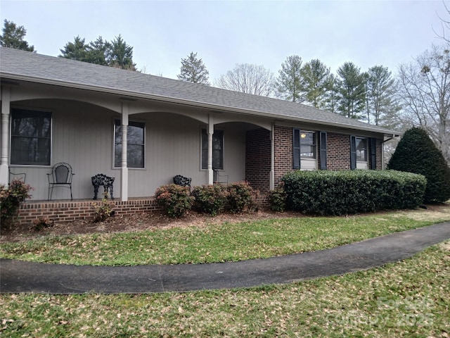 single story home with brick siding, covered porch, and a shingled roof