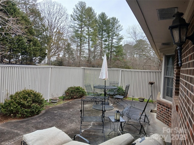 view of patio featuring outdoor dining area, visible vents, and fence