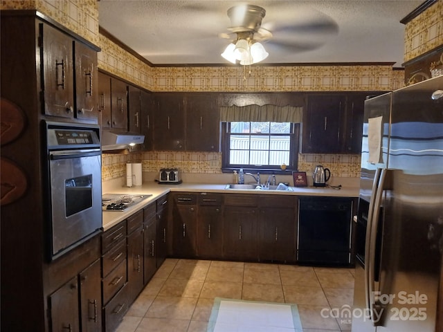 kitchen with a sink, under cabinet range hood, a textured ceiling, stainless steel appliances, and light countertops